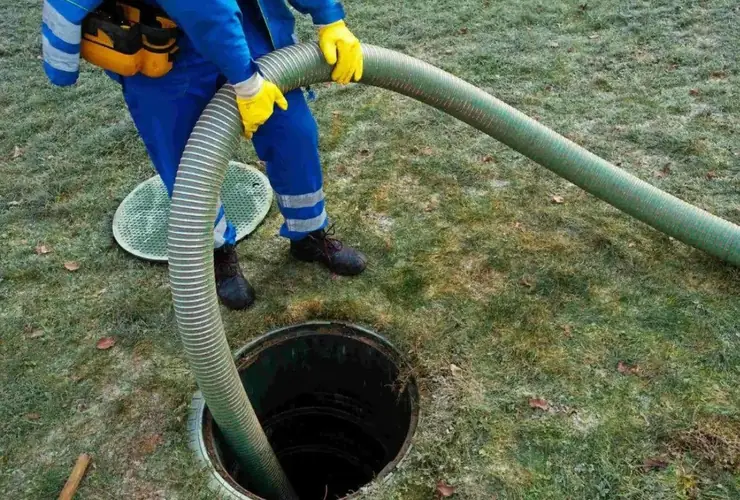 Technician pumping a septic tank with a vacuum hose